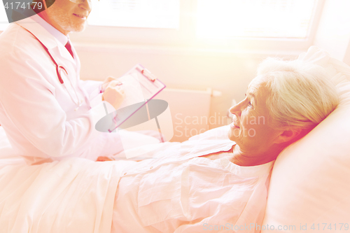 Image of senior woman and doctor with clipboard at hospital