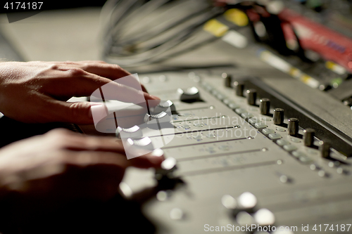 Image of hands on mixing console in music recording studio