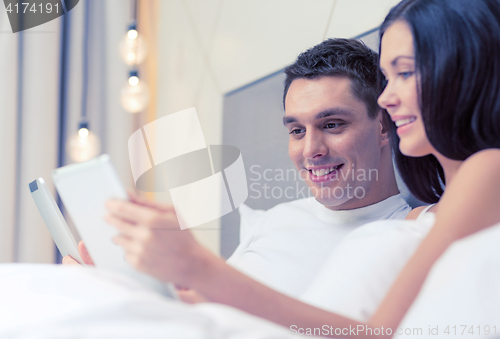 Image of smiling couple in bed with tablet pc computers