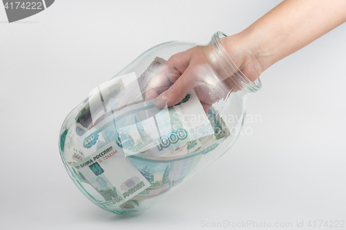 Image of Hand takes out a three-liter glass jars thousand Russian rubles