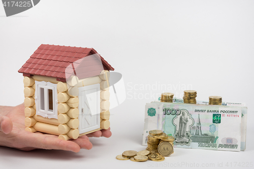 Image of The hands of toy house standing near the money is to buy housing