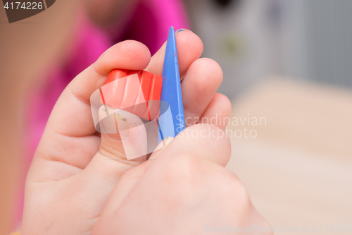 Image of The child cuts off a piece of a stack of red clay