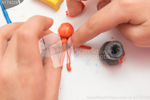 Image of Children\'s hands molded man from clay