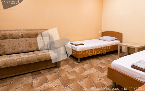 Image of The interior of a small room with a sofa and two beds