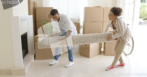 Image of Young couple carrying a rolled rug into a house