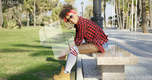 Image of Smiling trendy young woman on a marble bench