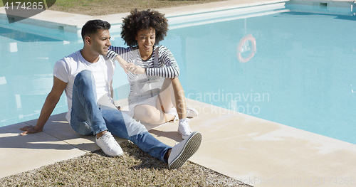 Image of Young woman relaxing with her boyfriend poolside