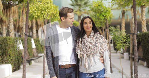 Image of Trendy young couple walking along a promenade