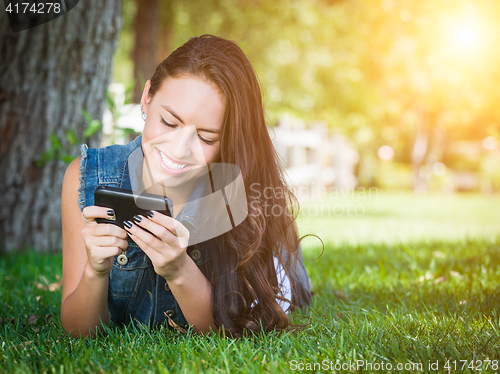 Image of Mixed Race Young Female Texting on Cell Phone Outside In The Gra