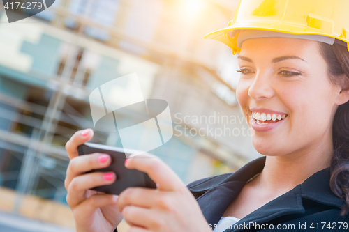 Image of Female Contractor Wearing Hard Hat on Site Texting with Cell Pho