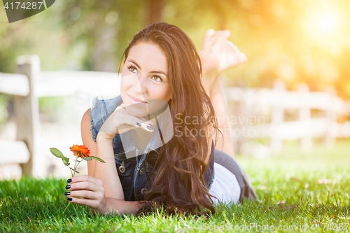 Image of Attractive Mixed Race Girl Holding Flower Portrait Laying in Gra