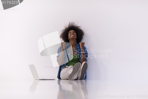 Image of african american woman sitting on floor with laptop