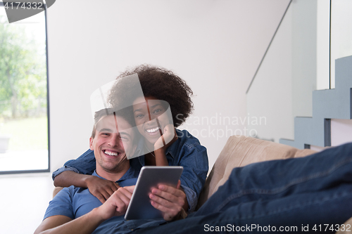 Image of multiethnic couple relaxing at  home with tablet computers