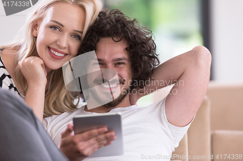 Image of couple relaxing at  home with tablet computers