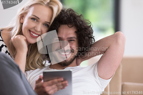 Image of couple relaxing at  home with tablet computers