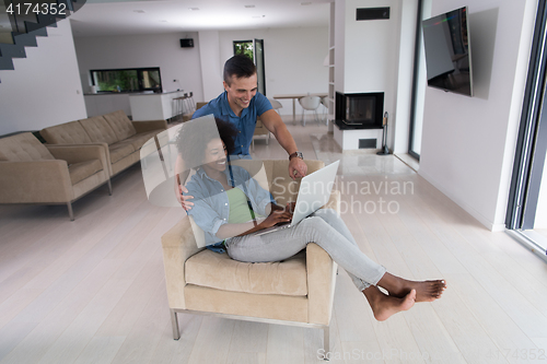 Image of multiethnic couple on an armchair with a laptop