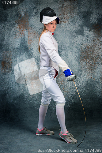 Image of The woman wearing fencing suit with sword against gray