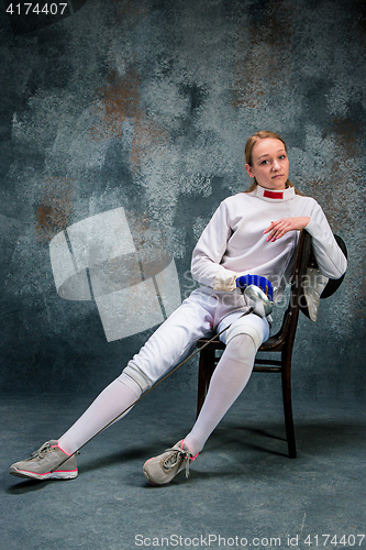 Image of The woman wearing fencing suit with sword against gray