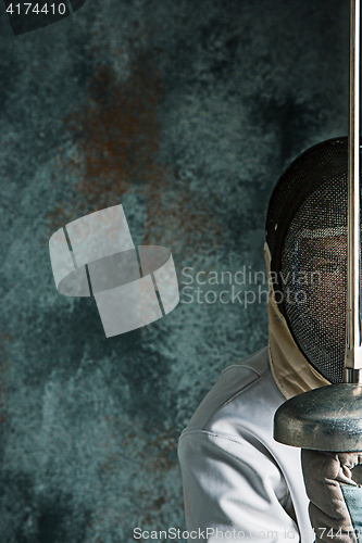 Image of The man wearing fencing suit with sword against gray