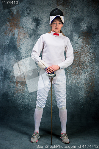 Image of The woman wearing fencing suit with sword against gray