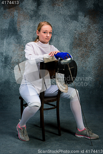 Image of The woman wearing fencing suit with sword against gray