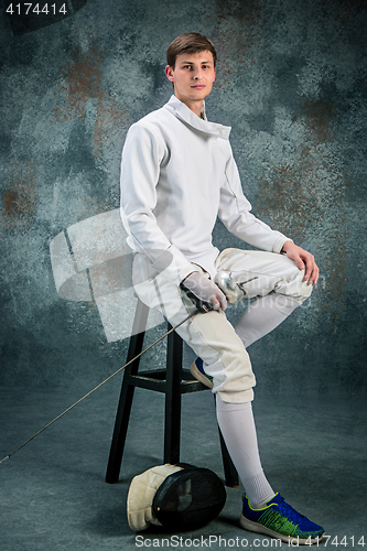 Image of The man wearing fencing suit with sword against gray