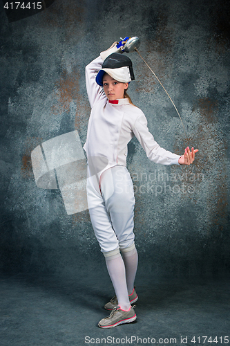 Image of The woman wearing fencing suit with sword against gray