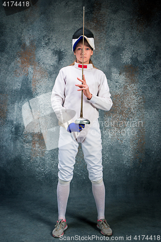 Image of The woman wearing fencing suit with sword against gray