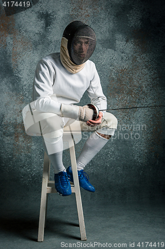 Image of The man wearing fencing suit with sword against gray