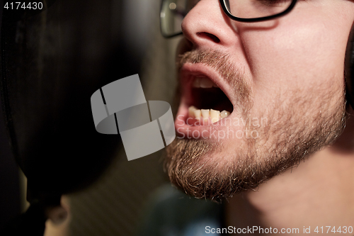 Image of man with headphones singing at recording studio