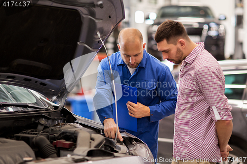 Image of auto mechanic with clipboard and man at car shop