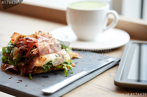 Image of prosciutto ham salad on stone plate at restaurant