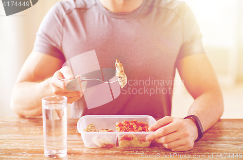 Image of close up of man with fork and water eating food