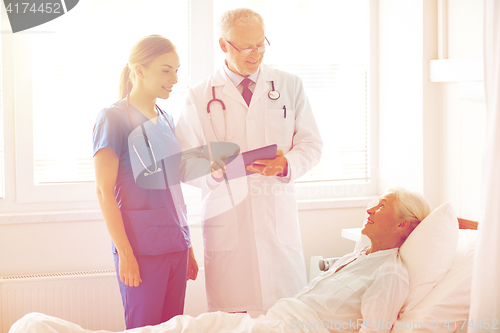 Image of doctor and nurse visiting senior woman at hospital