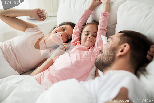 Image of happy family waking up in bed at home