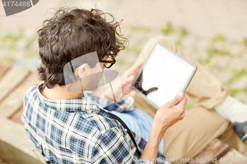 Image of man with tablet pc sitting on city street bench