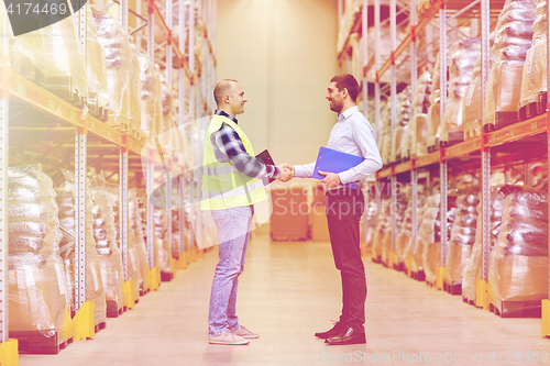 Image of worker and businessmen with clipboard at warehouse