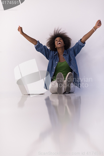 Image of african american woman sitting on floor with laptop