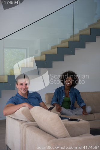 Image of multiethnic couple relaxing at  home with tablet computers