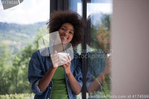 Image of African American woman drinking coffee looking out the window