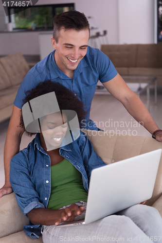 Image of multiethnic couple on an armchair with a laptop