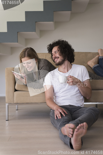 Image of couple relaxing at  home with tablet computers