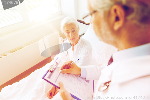 Image of senior woman and doctor with clipboard at hospital