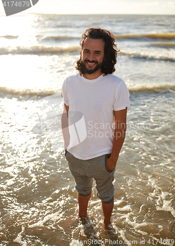 Image of happy man in white t-shirt on beach over sea