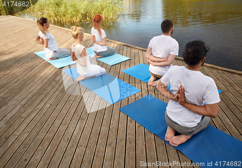 Image of group of people making yoga exercises outdoors