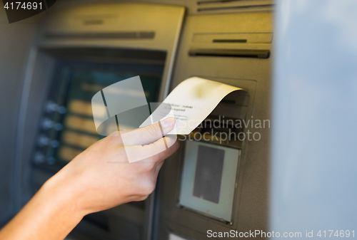 Image of close up of hand taking receipt from atm machine