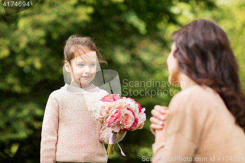 Image of girl giving with flowers to mother in summer park