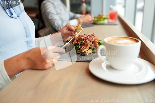 Image of woman eating prosciutto ham salad at restaurant