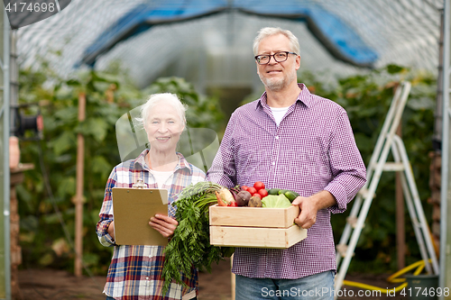 Image of senior couple with box of vegetables on farm