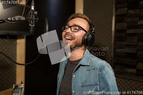 Image of man with headphones singing at recording studio